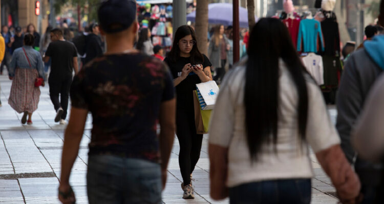 Personas comprando y transitando por un paseo peatonal