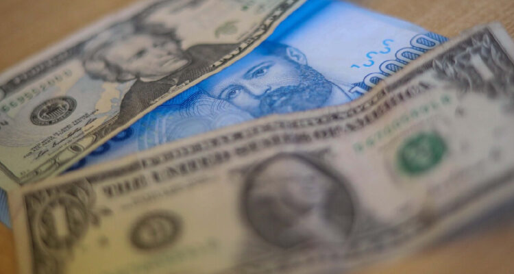 Un billete de 10 mil entre un billete de 20 dólares y otro de 1 dólar