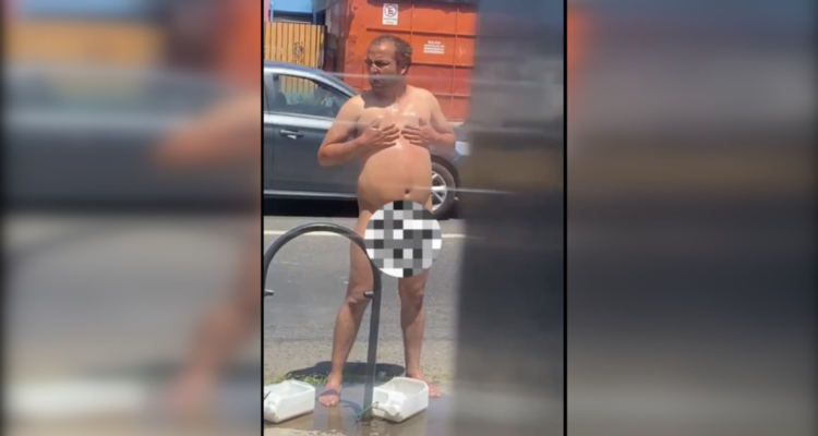 Hombre desnudo se baña en vía pública a plena luz del día con agua de perro