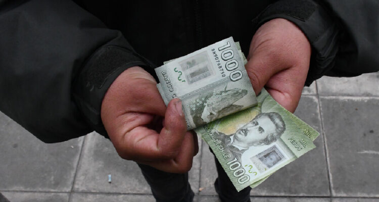 Hombre contando billetes de mil pesos