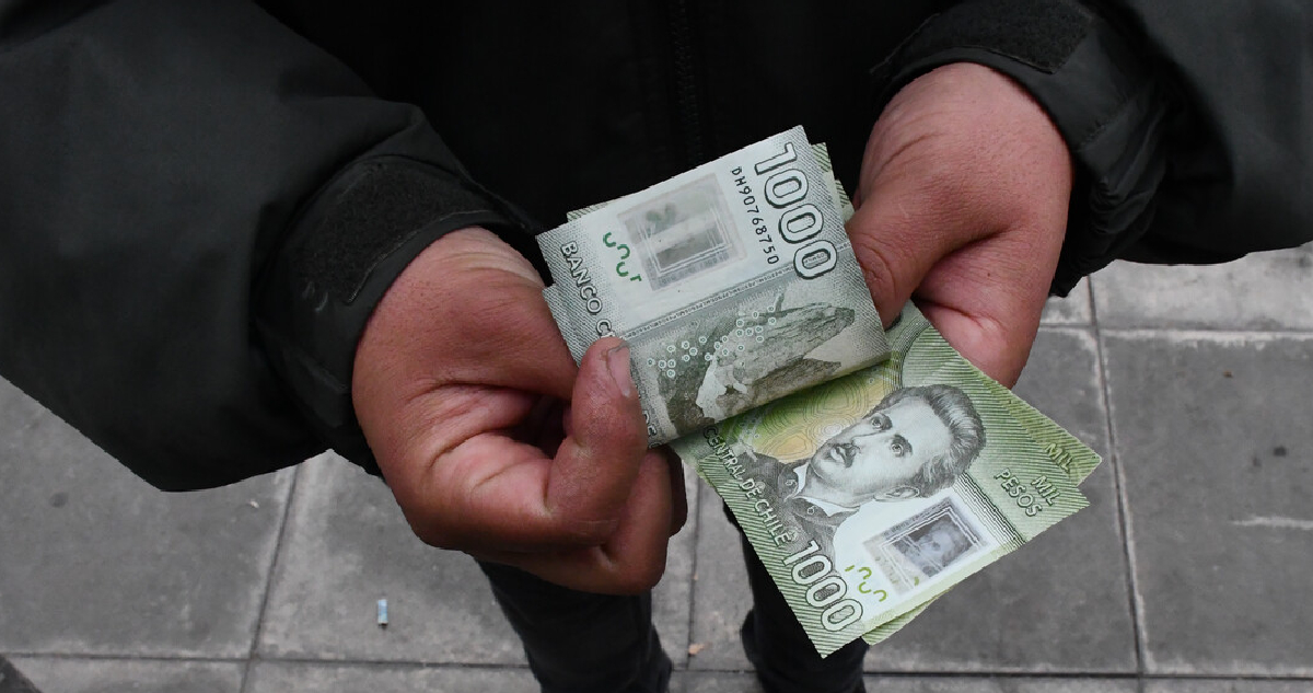 Hombre contando billetes de mil pesos
