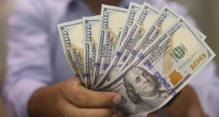 hombre sosteniendo varios billetes de 100 dólares