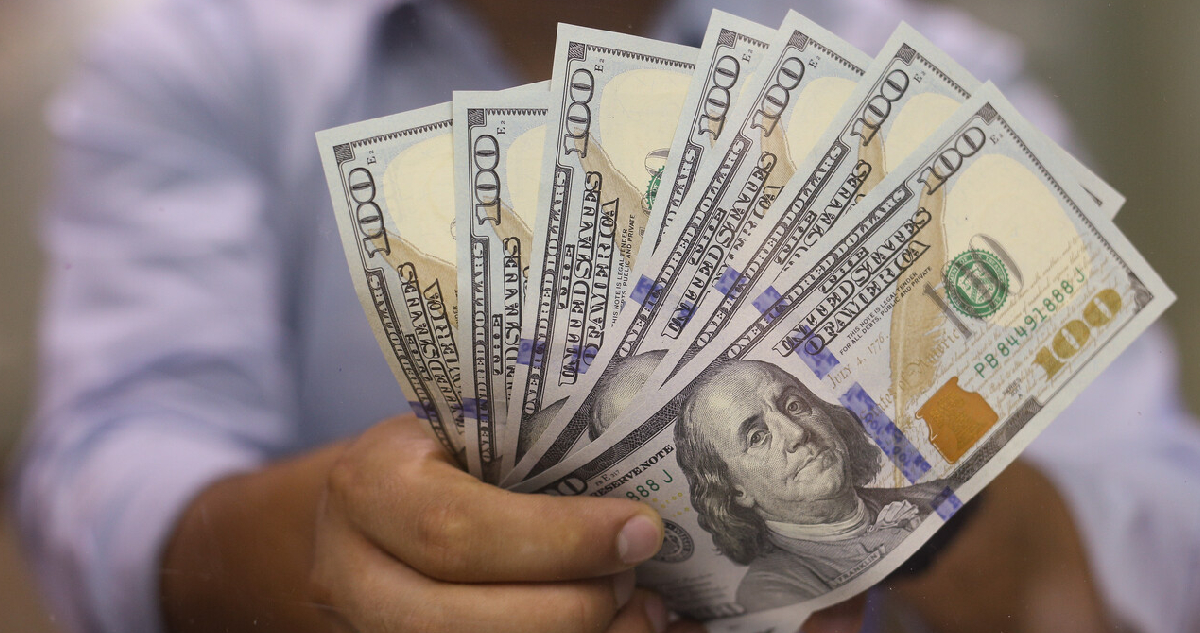 hombre sosteniendo varios billetes de 100 dólares