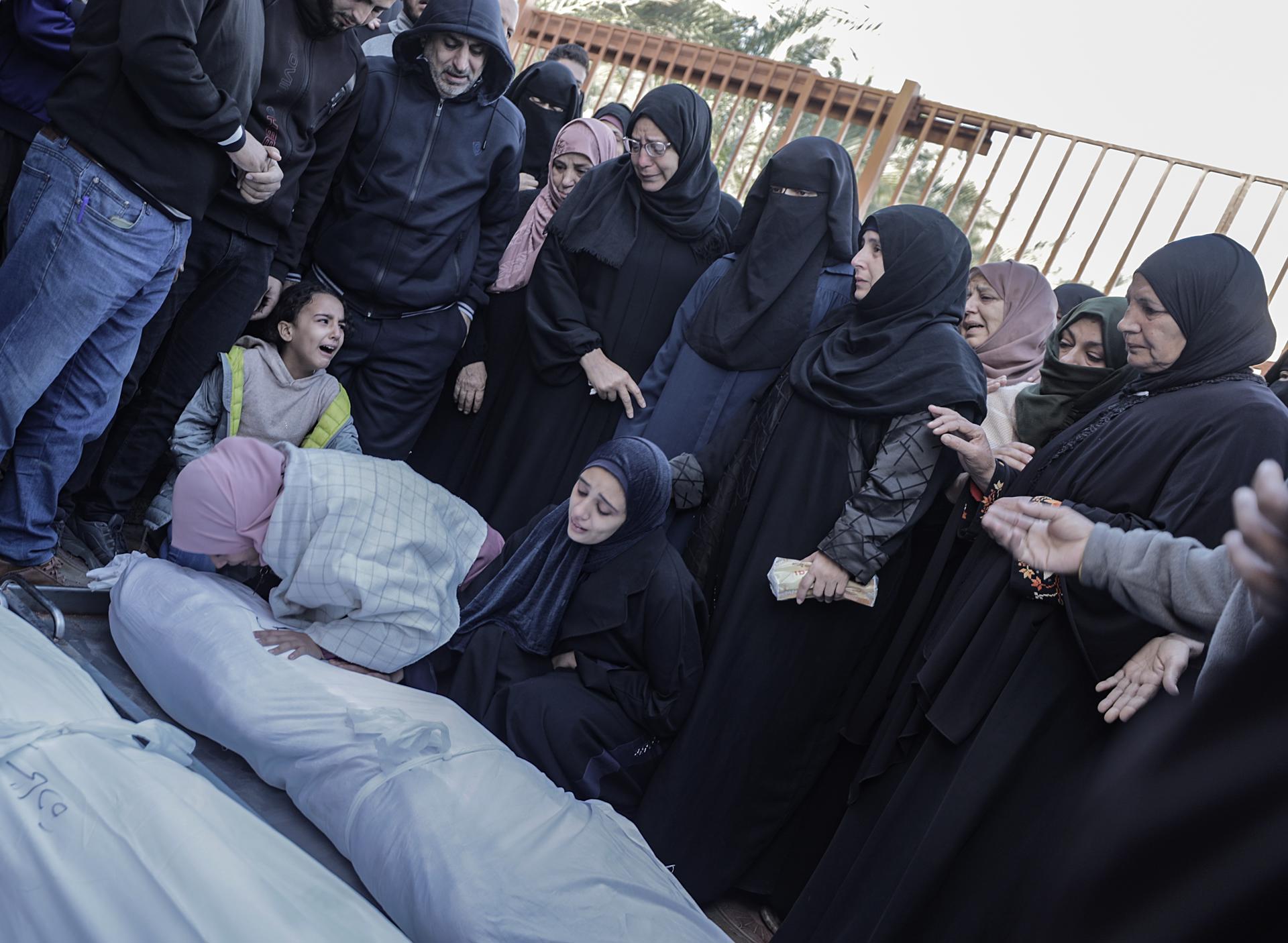Familiares de palestinos que murieron tras los ataques aéreos israelíes contra un edificio al sur de Gaza