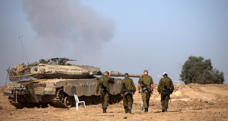 Un grupo de soldados israelíes camina cerca de un tanque en la frontera con la Franja de Gaza, en el sur de Israel.