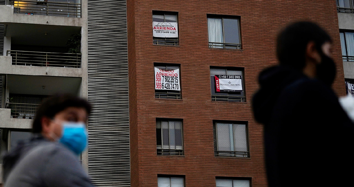 Personas pasan frente a un edificio con departamentos en arriendo y en venta en la comuna de Las Condes, durante la pandemia por Covid-19