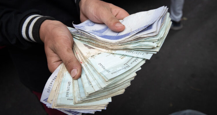 Un trabajador del transporte público muestra un fajo de bolívares, en Caracas (Venezuela)