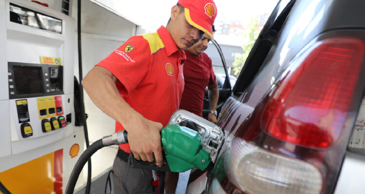 Trabajador de gasolinera echando combustible en un auto