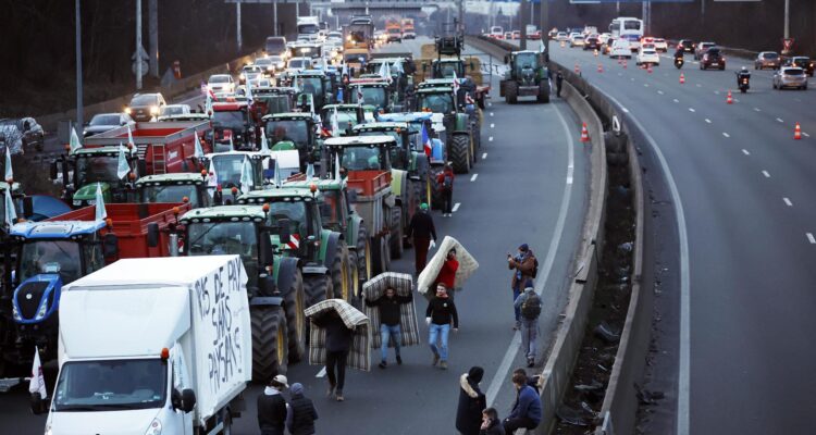 Agricultores llevan colchones para dormir en la autopista A-15 en Argenteuil, al norte de París