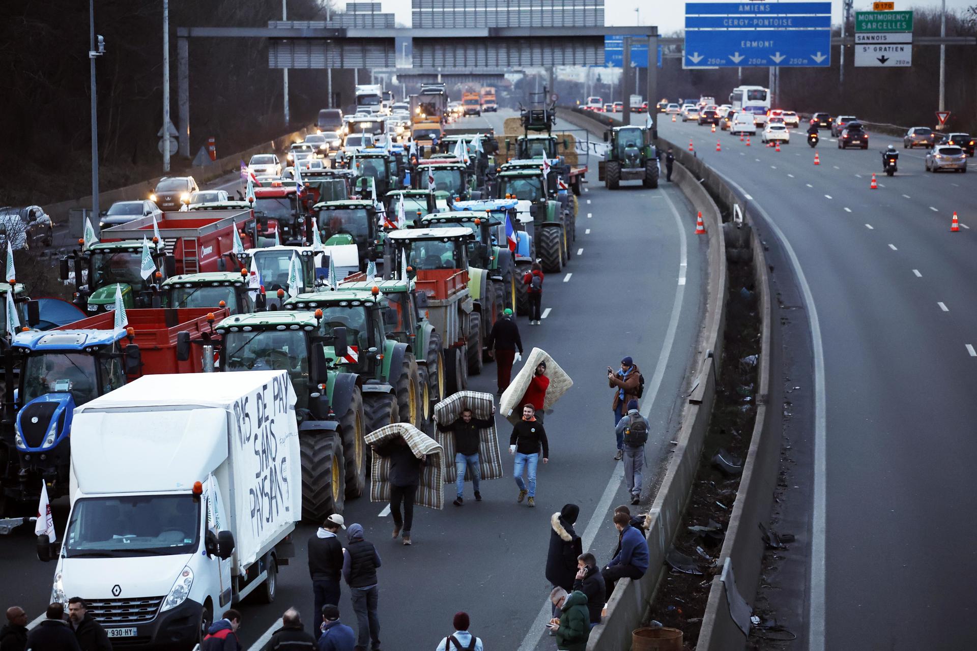 Agricultores llevan colchones para dormir en la autopista A-15 en Argenteuil, al norte de París