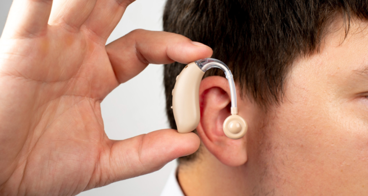 Hombre sosteniendo audífono en referencia a la asociación entre pérdida de audición y demencia