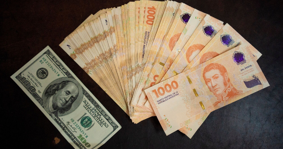 Un billete de 100 dólares junto a varios de mil pesos argentinos