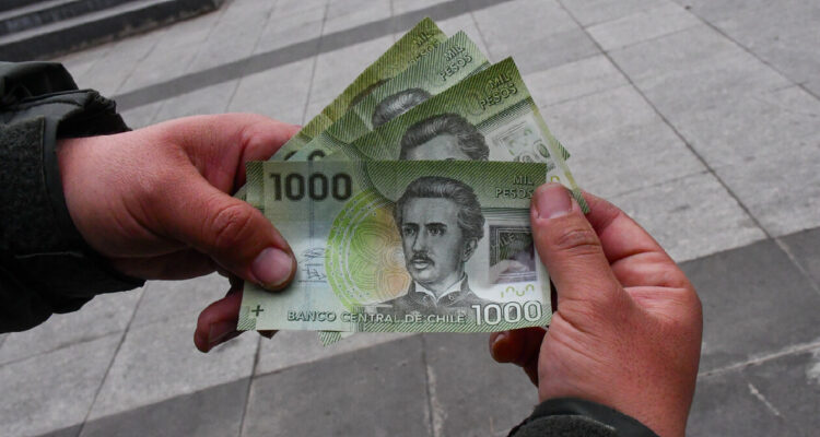una mano sosteniendo varios billetes de mil pesos