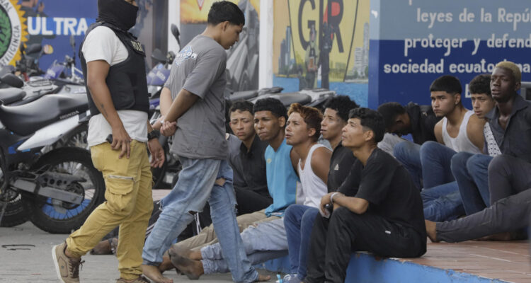 Un policía custodia hoy a los detenidos de un grupo armado por la toma temporal de un canal de televisión