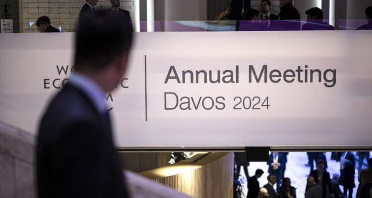 Un participante observa el logotipo del Foro Económico Mundial junto al título de encuentro anual davos 2024