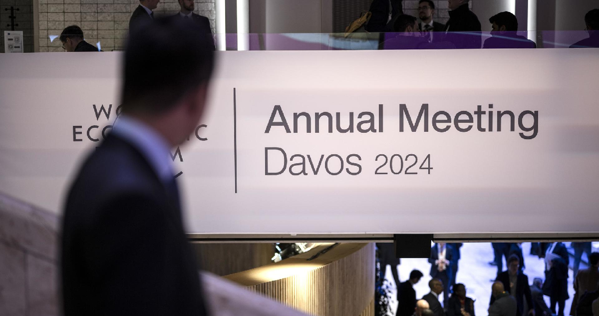 Un participante observa el logotipo del Foro Económico Mundial junto al título de encuentro anual davos 2024
