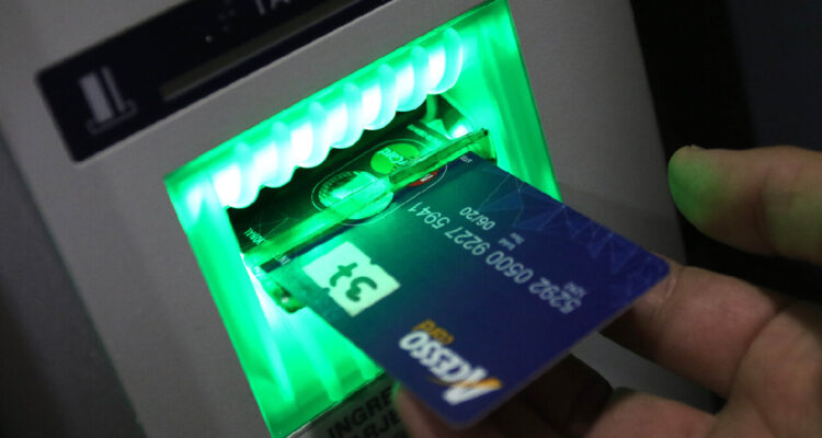 Una mano introduciendo una tarjeta en un cajero