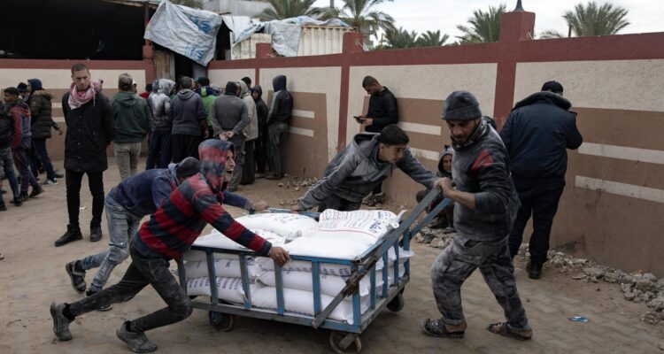 Palestinos cargan bolsas de harina distribuidas por la UNRWA en Rafah