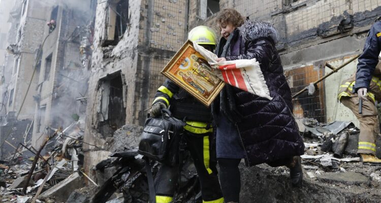 Los equipos de rescate evacuan a una mujer de un edificio dañado tras un ataque en Kiev