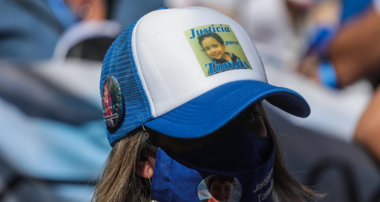 Mujer usando gorra con foto de Tomás Bravo por aplazamiento de preparación de juicio