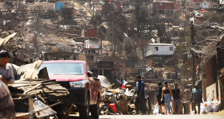 Personas trabajan removiendo escombros junto a voluntarios en el sector del paradero 10 de Achupallas, luego de los incendios forestales que afectaron a la ciudad de Viña del Mar.