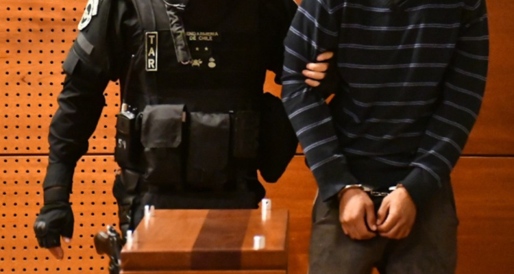 Imagen de contexto de un imputado siendo acompañado por un funcionario de Gendarmería la interior de la sala de un tribunal.