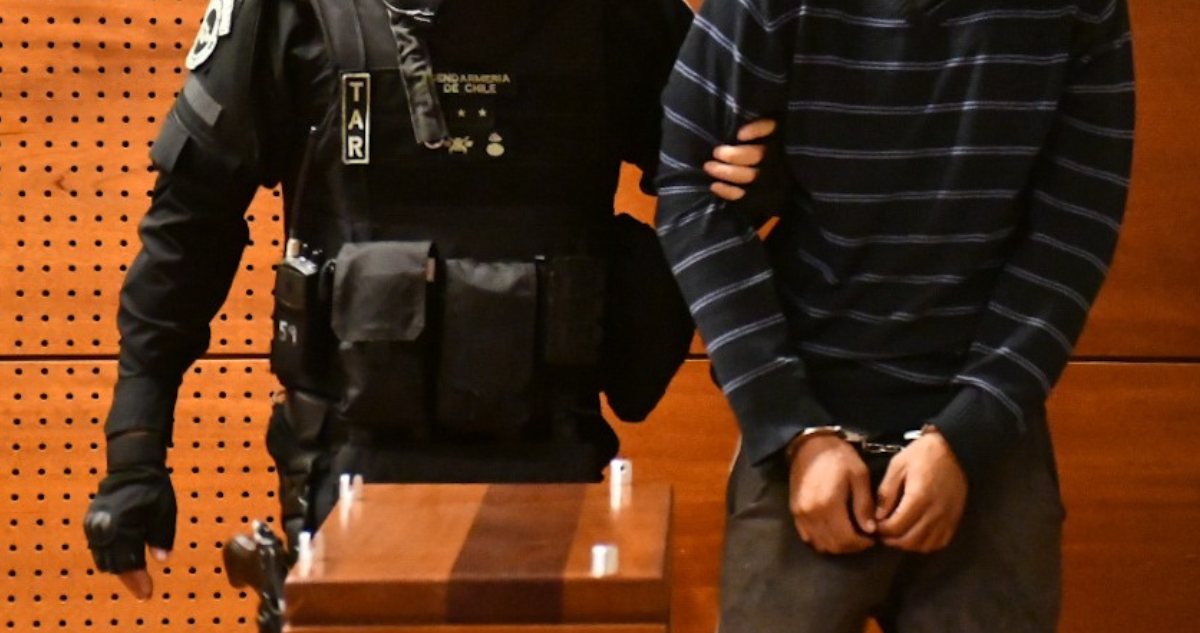Imagen de contexto de un imputado siendo acompañado por un funcionario de Gendarmería la interior de la sala de un tribunal.