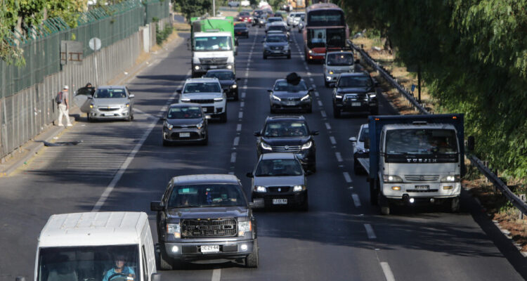 Diversos autos, camiones y un bus transitando por una carretera urbana