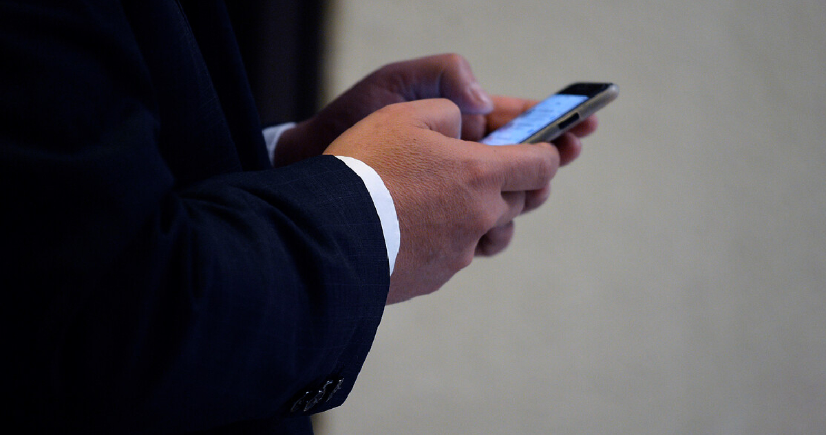 un hombre mirando un celular, plano detalle