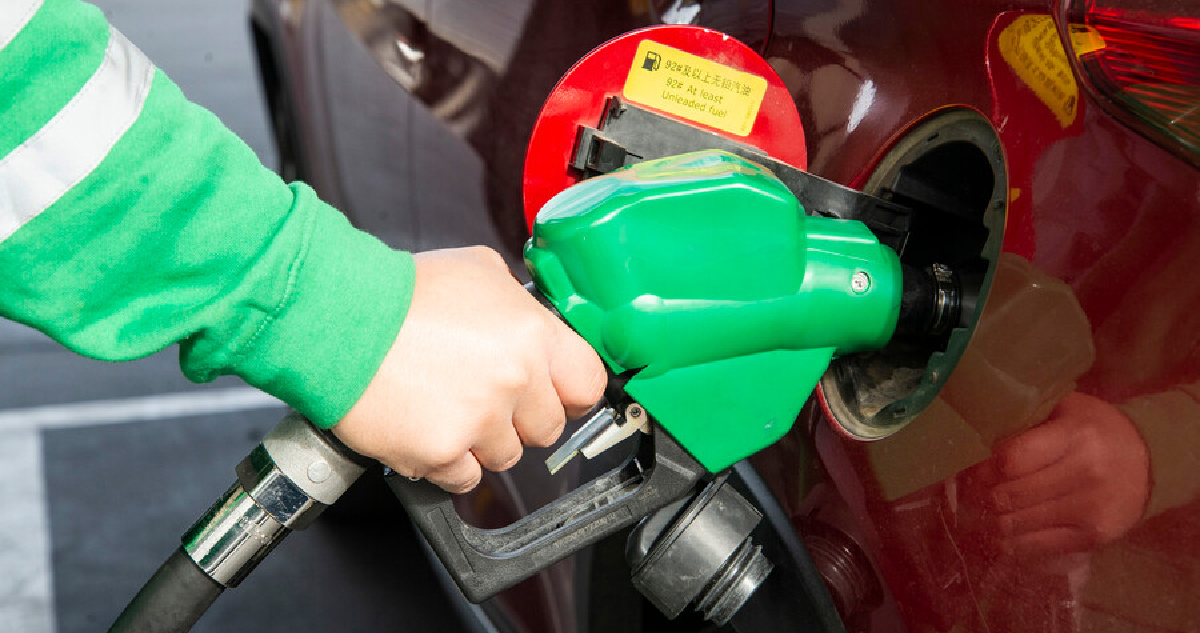 un bombero de estación de servicio usando un surtidor de combustible en un auto rojo