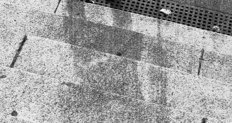 La sombra del residente de Hiroshima con bastón sentado en la escalinata del Banco Sumitomo.