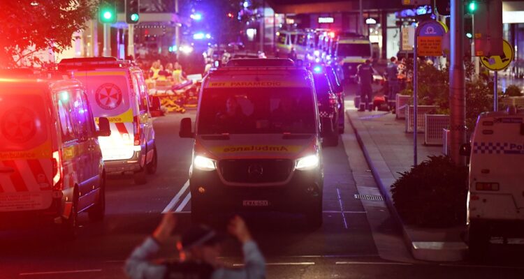 Sydney (Australia), 13/04/2024.- A police officer directs an ambulance after police responded to reports of multiple stabbings inside the Westfield Bondi Junction shopping centre in Sydney, Australia, 13 April 2024. New South Wales Police confirmed that at least six people died following a knife attack carried out by a man who was later shot dead by police. Several others were hospitalized with some in critical conditions.