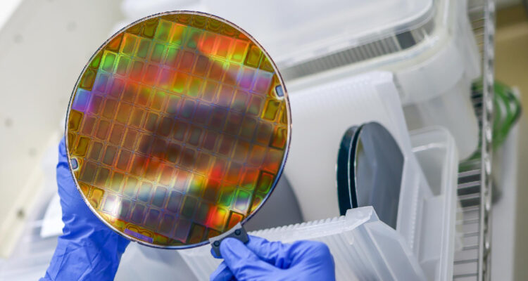 un hombre sostiene una oblea de material semiconductor, el cual se convertirá luego en chips