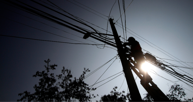 Trabajador trabajando en un poste a contraluz