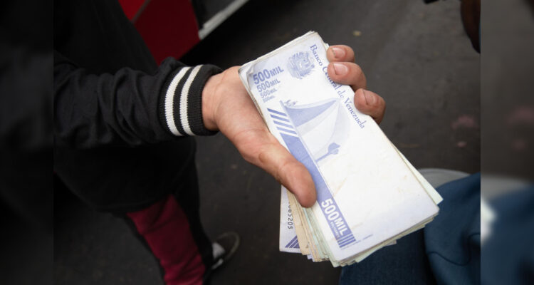 Un trabajador del transporte público muestra un fajo de bolívares, en Caracas (Venezuela) 30 de marzo de 2023