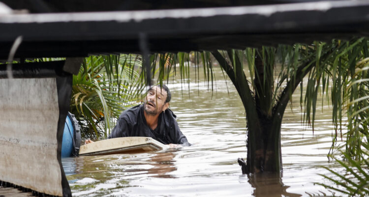 Un hombre sobre una tabla entre las calles inundadas del barrio Humaita, Porto Alegre
