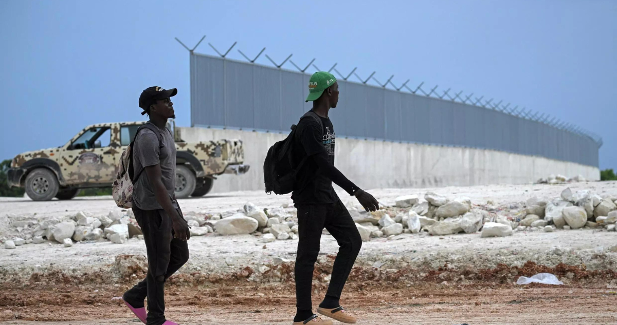 Ciudadanos haitianos pasan junto al muro fronterizo que se está construyendo en la frontera