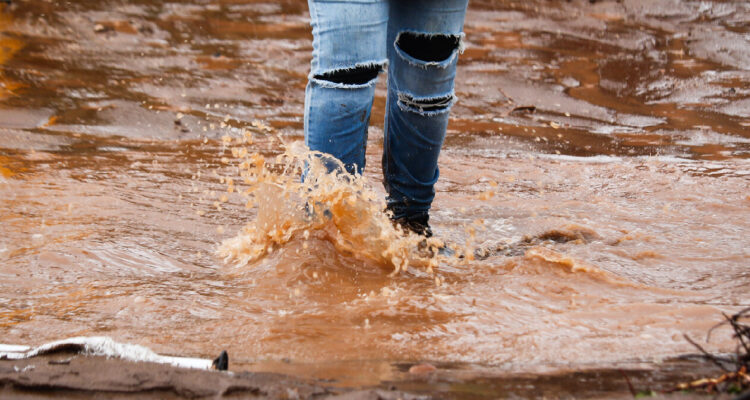 una persona con los pies en el agua y barro