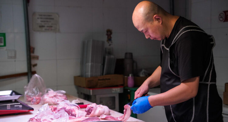 Un vendedor corta carne de cerdo local en un mercado de Pekín (China), hoy 17 de junio de 2024.