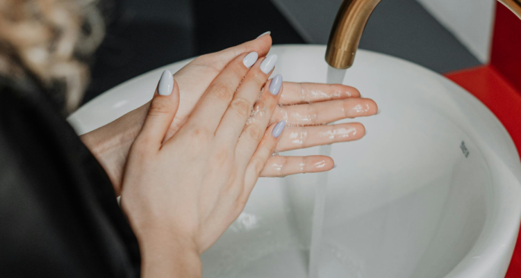 Mujer lavandose las manos en referencia a uso de toallas de papel o secador de aire para evitar bacterias