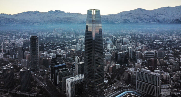 Vista de drone de la cordillera nevada al amanecer, con el costanera center en primer plano