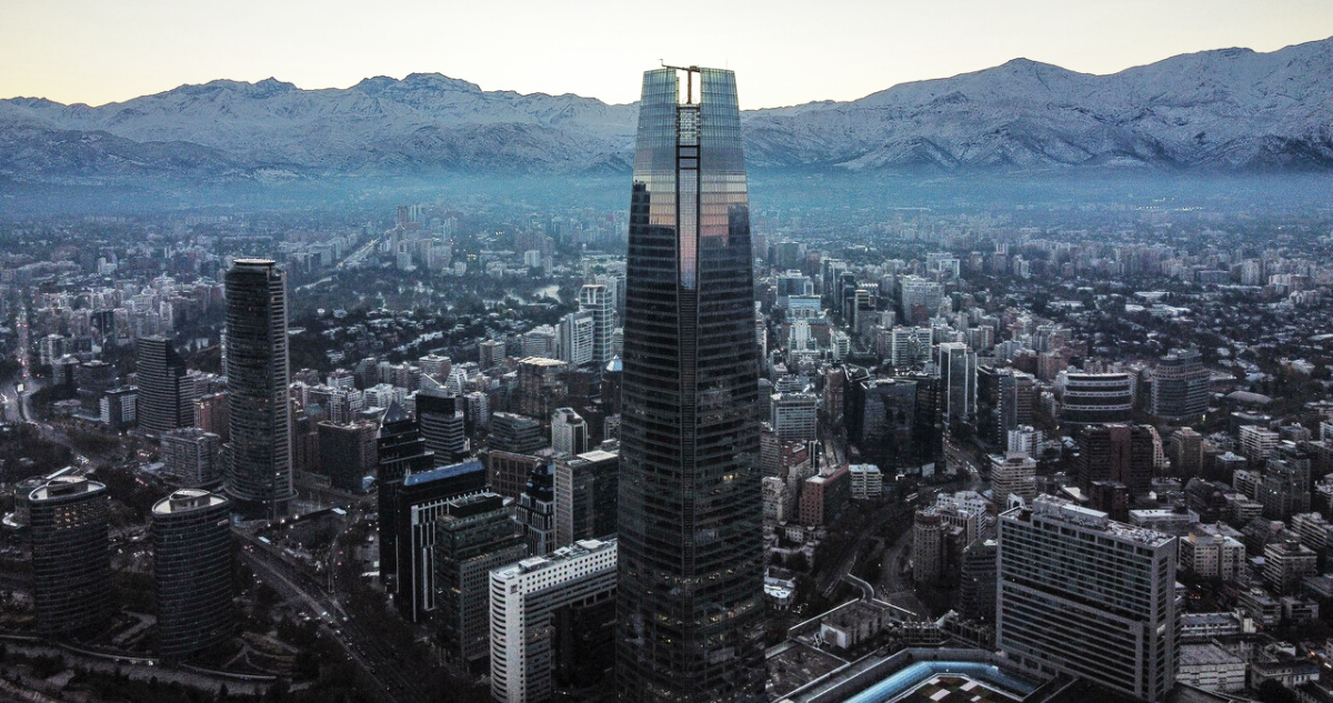 Vista de drone de la cordillera nevada al amanecer, con el costanera center en primer plano