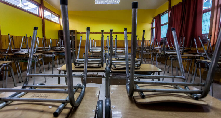 imagen de una sala de clases vacías y con sillas arriba de las mesas