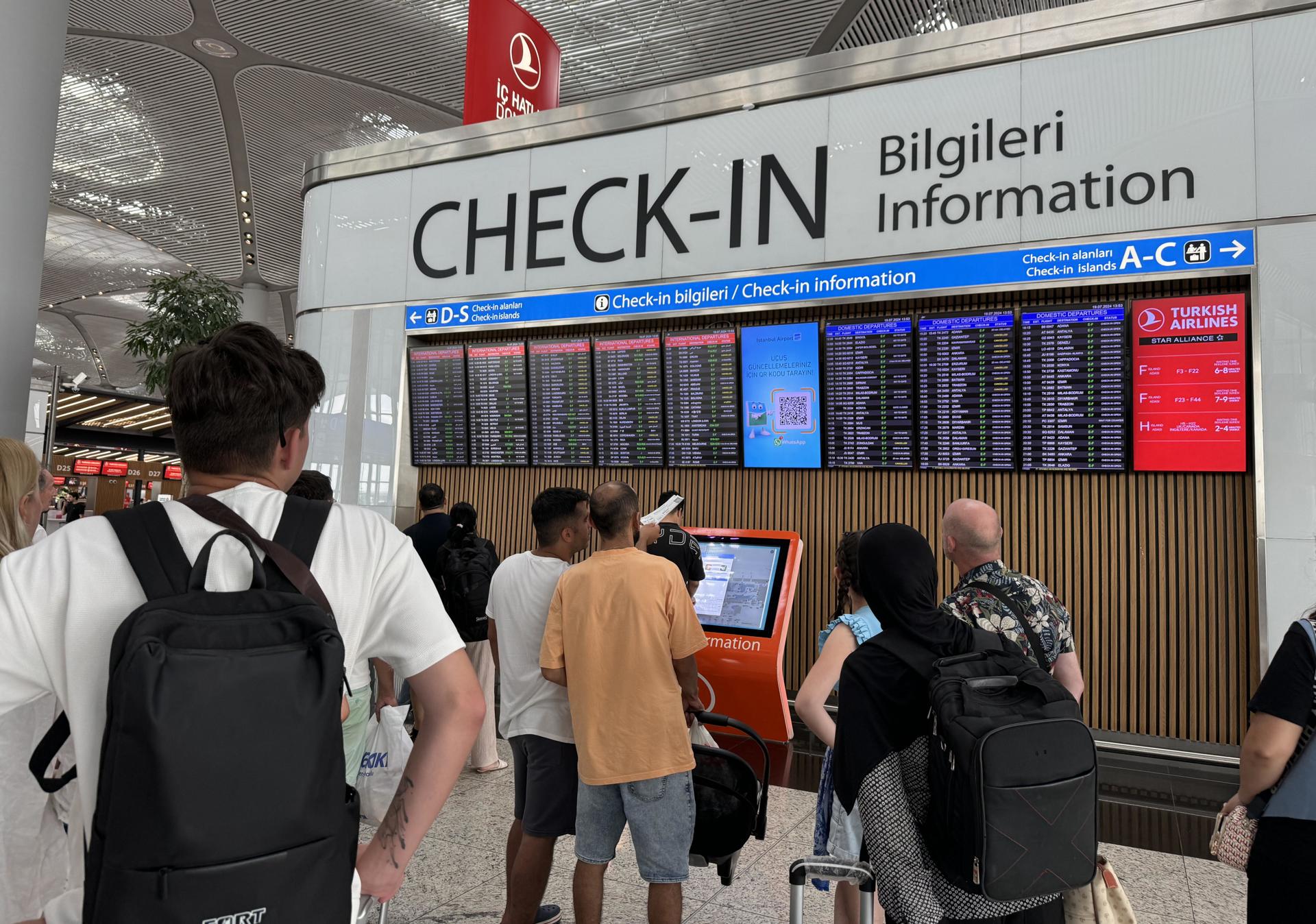 Los pasajeros consultan los paneles de información de vuelos en el aeropuerto de Estambul, Turquía