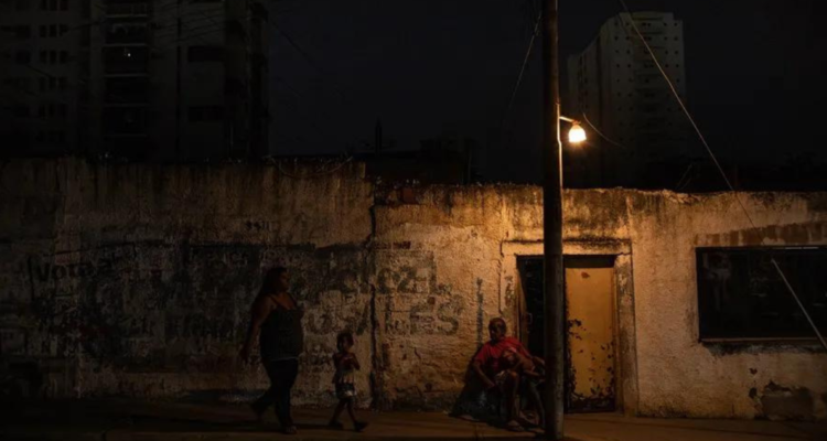 Un hombre descansa bajo un poste de luz, el 29 de febrero de 2024, en Maracaibo