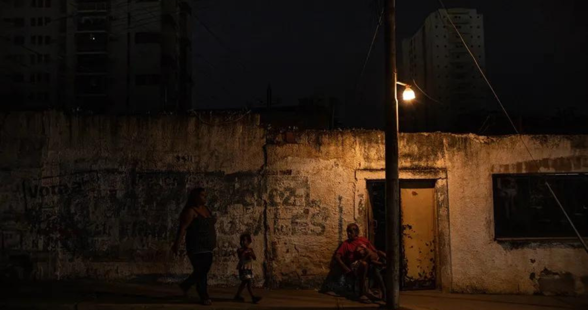 Un hombre descansa bajo un poste de luz, el 29 de febrero de 2024, en Maracaibo