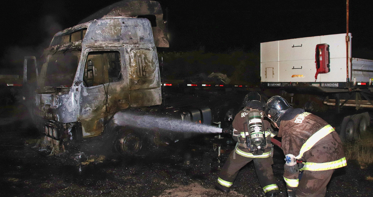 Bomberos sofocando fuego de camión quemado