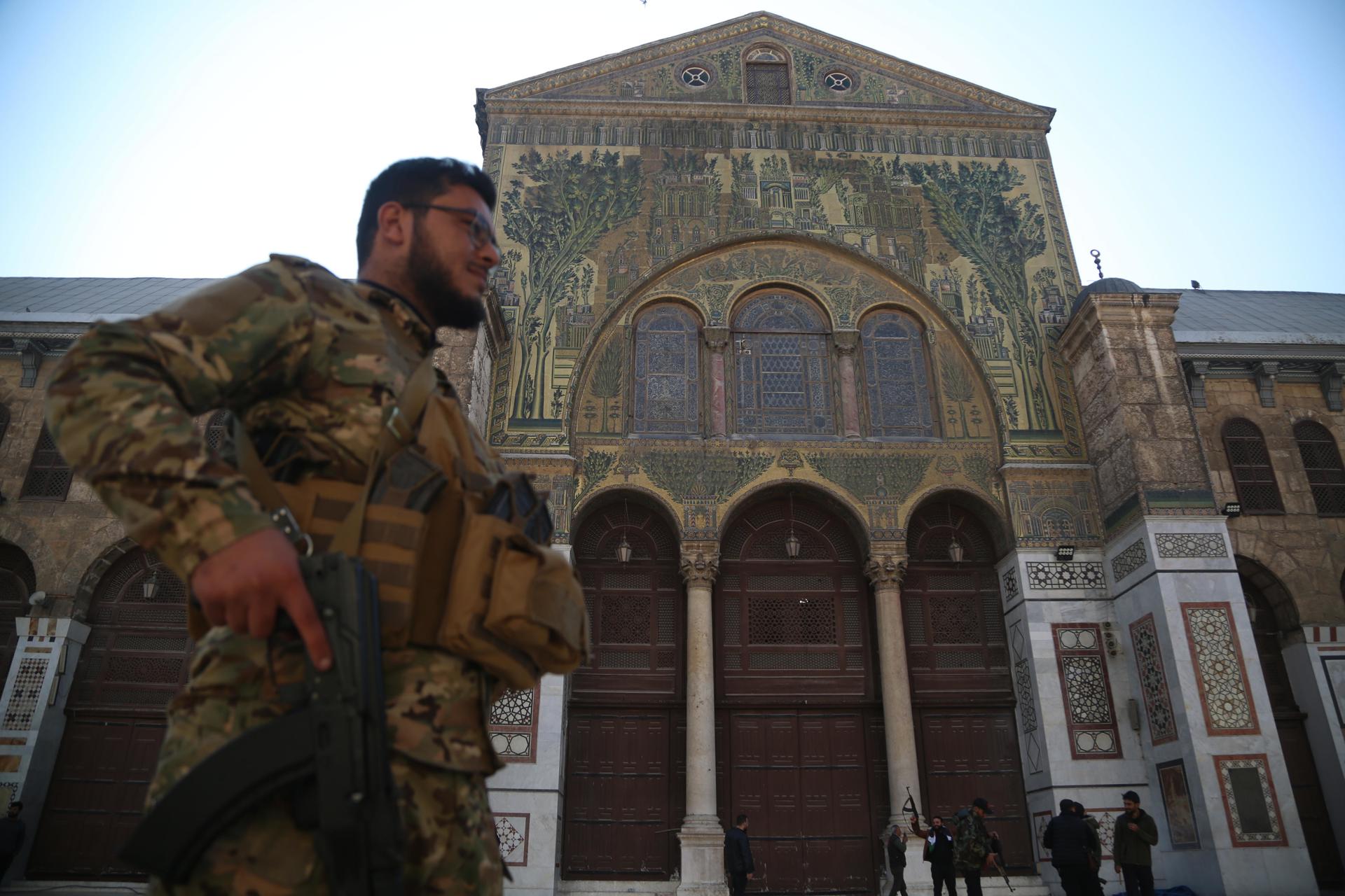 Un rebelde armado camina en la mezquita de los Omeyas en Damasco, Siria