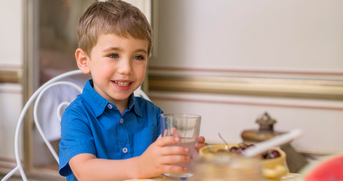 Niños que beben agua con la comida