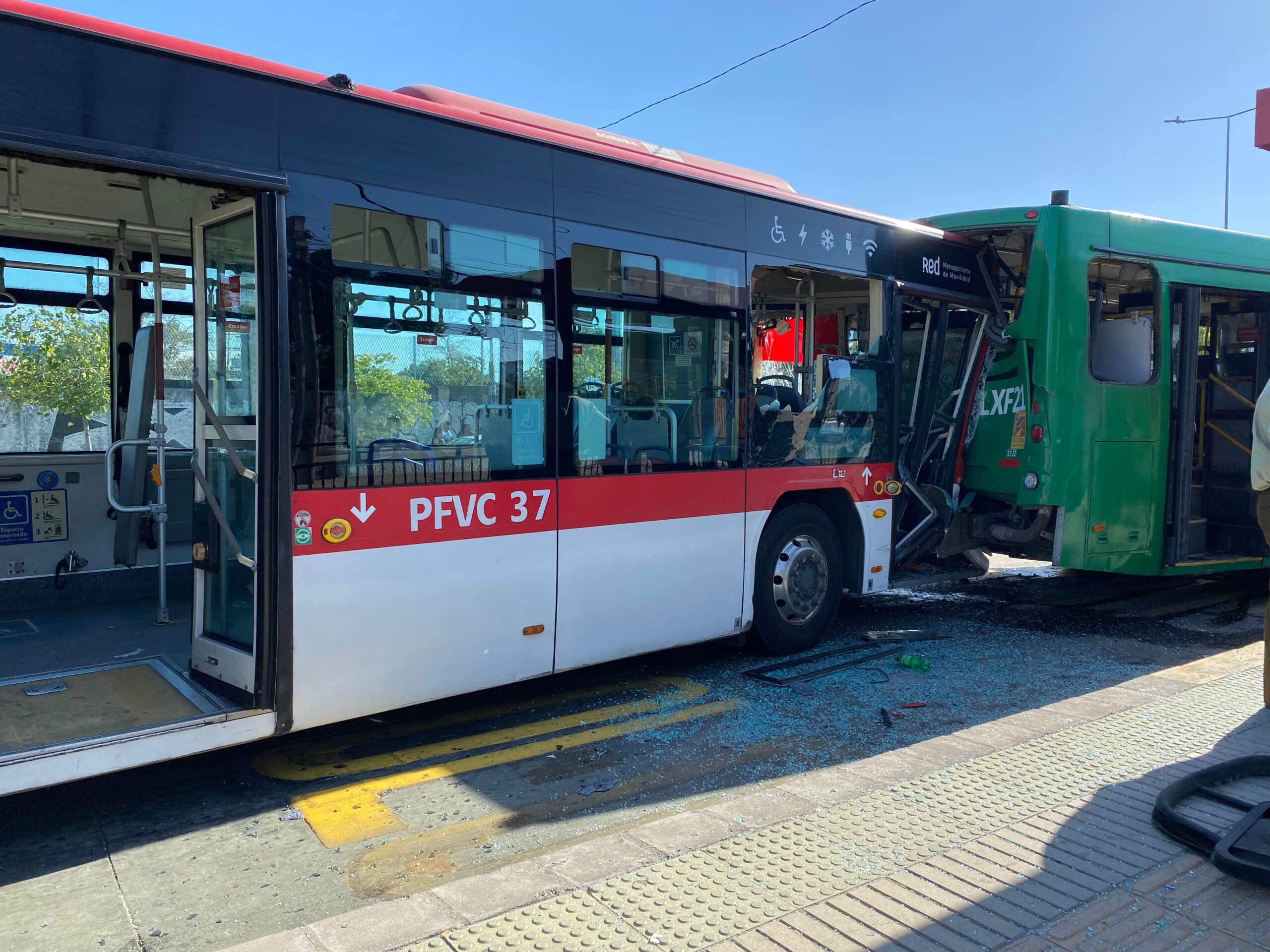 Dos buses, uno rojo con blanco y otro verde, choque